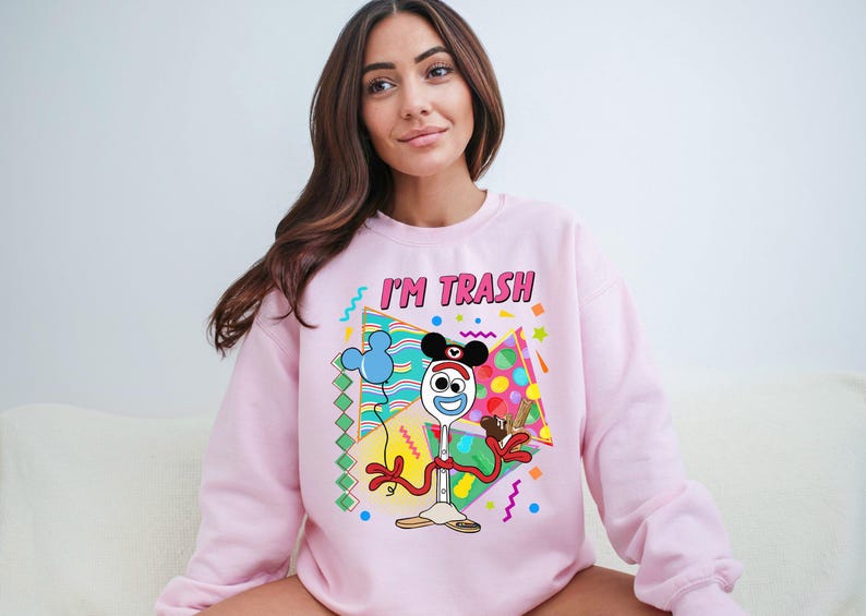 a woman sitting on a couch wearing a pink sweatshirt