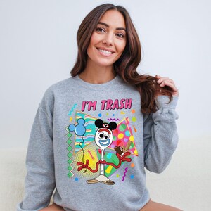 a woman sitting on a couch wearing a mickey mouse sweatshirt