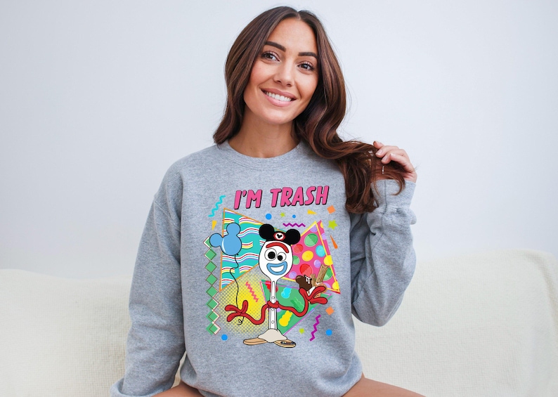 a woman sitting on a couch wearing a mickey mouse sweatshirt