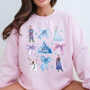 a woman sitting on a couch wearing a pink sweater