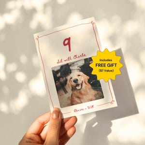 May include: A white card with red borders and handwritten text. The card has the number 9, the text "Sit with Charlie", and a photo of a golden retriever dog. The card also includes a yellow star with the text "Includes FREE GIFT ($7 Value)".