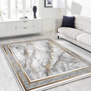 Può includere: Un tappeto bianco e oro con un motivo a marmi e un bordo a chiave greca. Il tappeto ha un leggero luccichio ed è perfetto per aggiungere un tocco di eleganza a qualsiasi stanza.