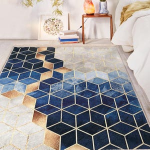 May include: A geometric rug with a blue, gold, and white pattern. The rug features a repeating pattern of hexagonal shapes with a 3D effect.