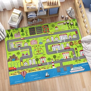 Op de afbeelding: Een groene speelmat met een stadswegontwerp. De mat heeft een verscheidenheid aan gebouwen, waaronder een school, een ziekenhuis, een tankstation, een bandencentrum, een markt, een museum en een circus. Er zijn ook auto's, vrachtwagens en een boot op de mat.