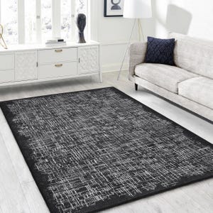 May include: Black and white area rug with a distressed, textured design. The rug has a geometric pattern with a subtle sheen.
