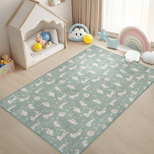 Puede incluir: Una alfombra de juego verde y blanca con un patrón repetido de conejos y flores. La alfombra es perfecta para la sala de juegos o el dormitorio de un niño.