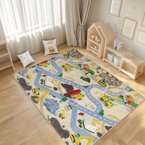 Può includere: Un tappeto da gioco beige e blu a tema edile. Il tappeto presenta veicoli da costruzione gialli, cumuli di terra e strade.