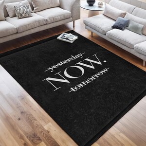 May include: Black rug with white text that reads "yesterday - NOW - tomorrow".