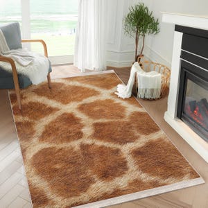 May include: A brown and white patterned rug with a faux fur texture. The rug has a light brown background with white spots and stripes.