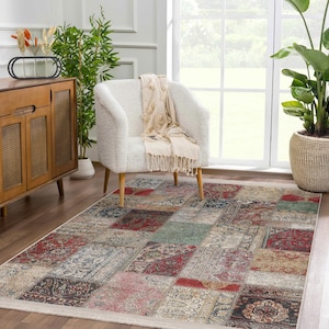 Puede incluir: Una alfombra de patchwork multicolor con un aspecto desgastado. La alfombra tiene un fondo crema con cuadrados de rojo, azul, verde y beige. La alfombra está en un salón con un sillón blanco y un armario de madera.