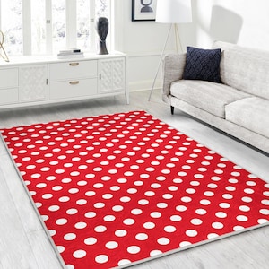 Puede incluir: Una alfombra rectangular roja con un patrón de lunares blancos. La alfombra está colocada sobre un suelo de madera clara en un salón. El patrón de la alfombra crea un contraste llamativo.