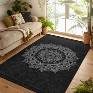 Puede incluir: Alfombra mandala en blanco y negro con un diseño detallado. La alfombra tiene un fondo negro y un patrón de mandala blanco.