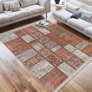 Könnte beinhalten: Ein Patchwork-Teppich mit cremefarbenem Hintergrund und braunen, beigefarbenen und rostfarbenen Quadraten. Der Teppich hat einen Used-Look und ist aus einem weichen, strapazierfähigen Material gefertigt.
