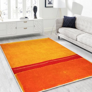 May include: Abstract area rug with a yellow, red, and orange color scheme. The rug has a modern, minimalist design with a single red stripe across the yellow background and a large orange rectangle in the lower right corner.