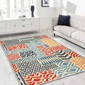 May include: A colorful area rug with a patchwork design featuring geometric patterns, stripes, and animal prints in shades of red, orange, blue, and white.