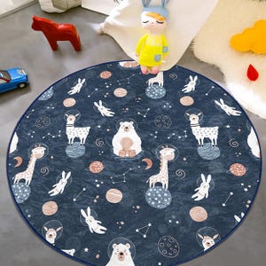 May include: A round blue play mat with a white border features a repeating pattern of white animals, stars, and planets on a dark blue background. The animals include giraffes, llamas, polar bears, and bunnies.