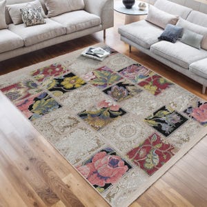 May include: A patchwork style rug with a beige background and colourful floral designs. The rug is made up of different squares with various floral patterns in shades of red, pink, yellow, green, and blue.