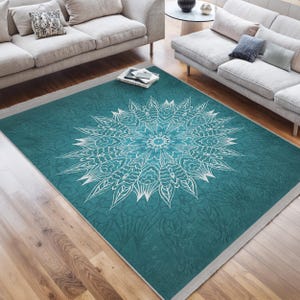 May include: Teal area rug with a white mandala design. The rug has a fringed edge.