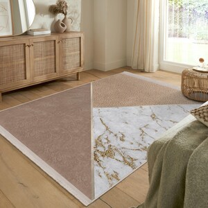 May include: A geometric area rug with a white marble design, a light brown section, and a beige section. The rug has a white border.