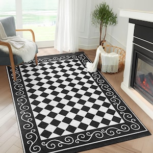 May include: Black and white chequered area rug with a decorative white border featuring a repeating swirl pattern. The rug has a diamond pattern.