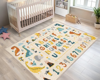 May include: A cream-colored alphabet and number rug with colorful dinosaurs, volcanoes, and plants. The rug features the alphabet, numbers 1-9, and the numbers 10-20.