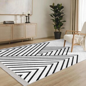 Może przedstawiać: Geometryczny dywan w kolorze czarno-białym o nowoczesnym designie. Dywan charakteryzuje się wzorem z nakładających się linii tworzących serię trójkątów i kwadratów.