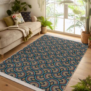 Könnte beinhalten: Ein blauer, beiger und roter Teppich mit einem weißen Rand. Der Teppich hat ein geometrisches Muster aus geschwungenen Linien und Punkten. Der Teppich liegt auf einem Holzboden in einem Wohnzimmer.