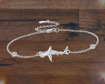 May include: Silver chain bracelet with a hammerhead shark charm and two clear cubic zirconia stones.
