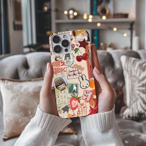 a person holding up a phone case with stickers on it