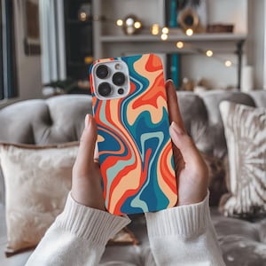 May include: A phone case with a colorful abstract design featuring swirls of blue, orange, red, and yellow. The case is made for a phone with a camera bump.