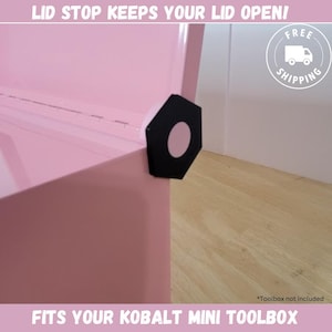 May include: A pink metal toolbox with a black lid stop that keeps the lid open. The lid stop is shaped like a hexagon with a round, pink center.