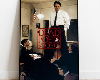 Könnte beinhalten: Ein gerahmtes Filmplakat für Dead Poets Society, das einen Lehrer zeigt, der in einem Klassenzimmer auf einem Schreibtisch steht, während Schüler an Tischen sitzen. Der Text Dead Poets Society steht in roten Großbuchstaben in einem roten Quadrat.