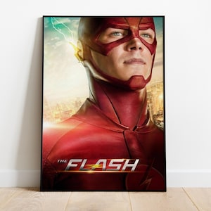 Könnte beinhalten: Ein gerahmtes Poster mit einer Nahaufnahme von The Flash, der einen strukturierten dunkelroten Anzug und eine Maske mit einem gelben Blitzemblem an der Seite trägt. Der Hintergrund zeigt eine verschwommene Stadt bei Sonnenuntergang mit dem Text THE FLASH.