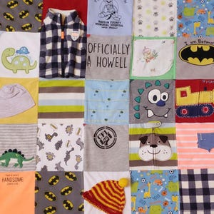 May include: A patchwork quilt made from baby clothes with various designs, including dinosaurs, a monster, a dog, a truck, and a Batman logo. The quilt also includes a small hat, a vest, and a shirt with the text "Officially a Howell" and "CFL 1363".