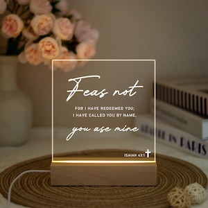 May include: A square, illuminated acrylic sign with the words "Fear not" and a Bible verse. The sign sits on a wooden base and is lit from below. The text reads "For I have redeemed you; I have called you by name, you are mine."