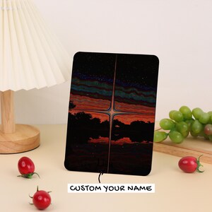May include: A black rectangular item with a colorful landscape design featuring a starry sky, trees, and a body of water. The text "CUSTOM YOUR NAME" is printed in white. The item is displayed on a light-colored surface.