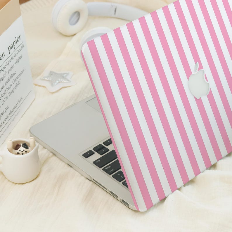 Op de afbeelding: Een roze en witte gestreepte laptop-huid met het Apple-logo. De huid is op een zilveren laptop.