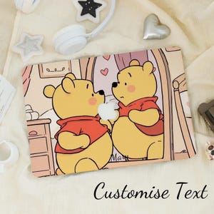 May include: A rectangular laptop skin with a cartoon illustration of two yellow bears in red shirts, holding a white apple. The background is a soft pink room with hearts. The words "Customise Text" are written at the bottom.