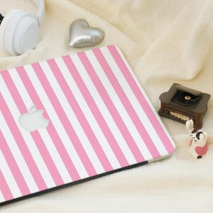 Op de afbeelding: Een roze en witte gestreepte laptop-skin met het Apple-logo in het midden.