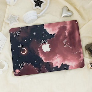 Könnte beinhalten: Eine Laptop-Hülle mit einem Himmelsdesign. Sie hat einen dunkelblauen Hintergrund mit rosa Wolken, weißen Sternen und einem Halbmond. Das Design umfasst ein weißes Apple-Logo und Katzenillustrationen. Ein dekoratives Zubehör für einen Laptop.