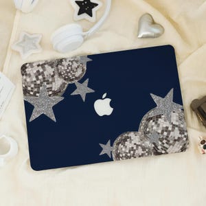 May include: A navy blue laptop case featuring a silver glitter star and disco ball design. The case has an Apple logo on the front.