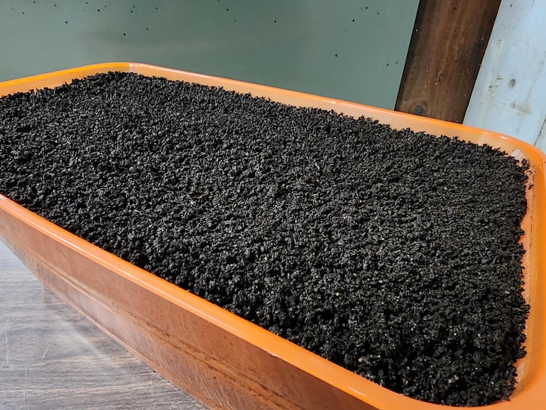 May include: A close-up of a terracotta-colored rectangular planter filled with dark brown compost.