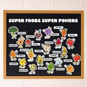 Op de afbeelding: Een ingelijst schoolbord met de tekst "SUPER FOODS SUPER POWERS" en cartoon illustraties van verschillende groenten en fruit. Elke afbeelding heeft een label dat de gezondheidsvoordelen beschrijft, zoals "Fiber Power" en "Vitamin C Boost".
