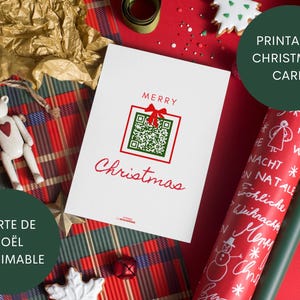 Peut inclure: Une carte de Noël blanche avec un nœud rouge et un code QR, les mots "Merry Christmas" en écriture rouge. La carte est sur une surface à carreaux avec un ornement d'ours en peluche et du papier d'emballage.