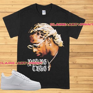 May include: Black t-shirt featuring a graphic of Young Thug wearing sunglasses and a gold chain. The text "Young Thug" is printed in white below the image.
