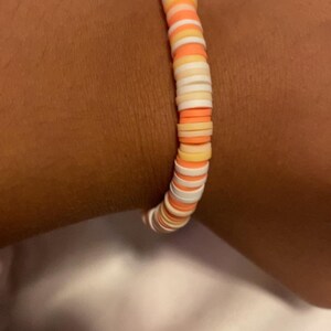 Peut inclure: Un bracelet color&eacute; compos&eacute; de perles rondes en plastique empil&eacute;es dans des tons de blanc, p&ecirc;che et orange.