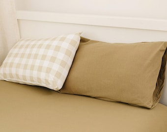 Peut inclure: Deux oreillers sur un lit. Un oreiller est de couleur unie beige et l'autre est à carreaux blancs et beiges.
