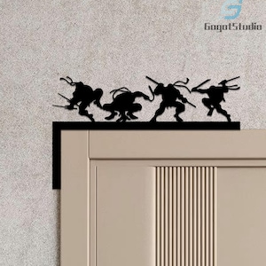 May include: Black metal wall art depicting the Teenage Mutant Ninja Turtles in action. The silhouettes of the four turtles are shown above a door, each holding their distinctive weapons. The artwork is a decorative piece.