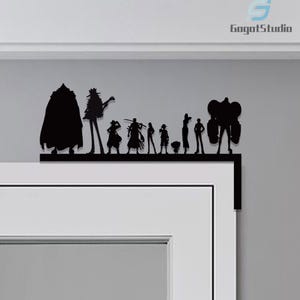 Puede incluir: Silueta negra de varios personajes, probablemente de una serie de anime o manga popular, montada sobre un marco de puerta. Las figuras est&aacute;n dispuestas en l&iacute;nea, con diferentes alturas y poses. El texto "GogotStudio" es visible.