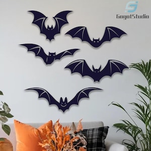 May include: Dark navy bat wall decorations in various poses, with outstretched wings and detailed wing structures. The bats are arranged on a white wall, creating a Halloween or gothic theme. The image includes a logo in the upper right corner.